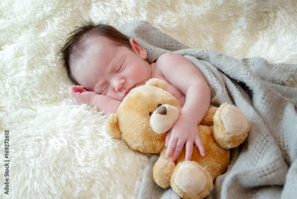 Cute newborn baby girl sleeps with a toy teddy bear Cute newborn baby girl sleeps with a toy teddy bear