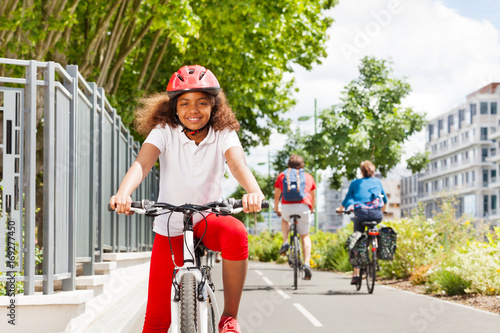 Happy African girl cycling on bicycle path in city