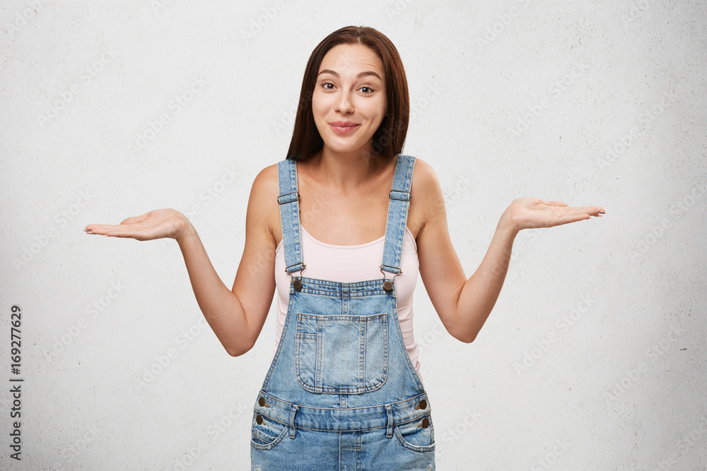 So what? Who cares? Isolated studio shot of positive Caucasian brunette girl shrugging her shoulders, looking careless about problems, having calm and carefree expression on her pretty face So what? Who cares? Isolated studio shot of positive Caucasian brunette girl shrugging her shoulders, looking careless about problems, having calm and carefree expression on her pretty face