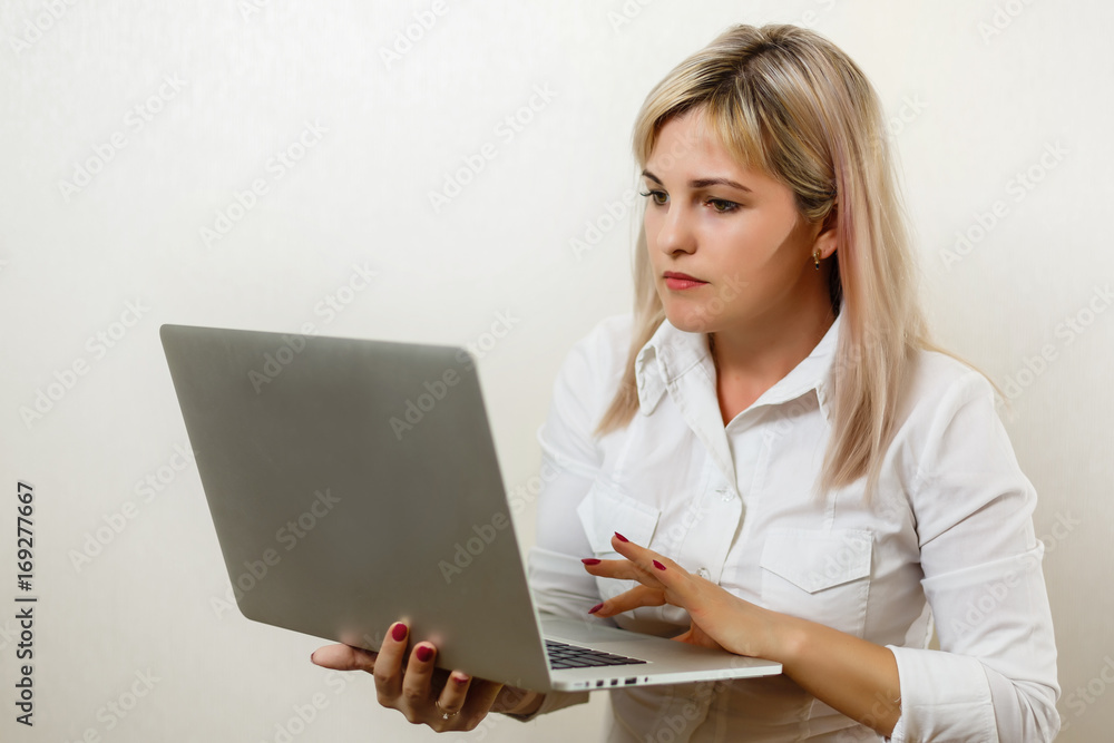 Smiling lovely young businesswoman standing and holding laptop over white background Smiling lovely young businesswoman standing and holding laptop over white background