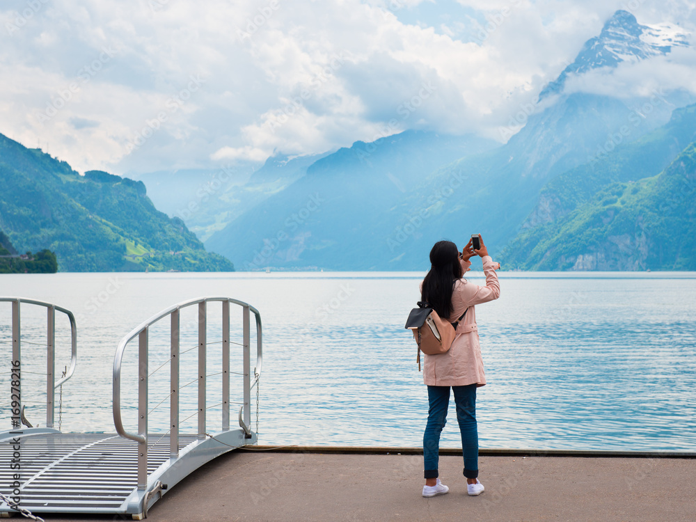 Brunnen, Switzerland - 30.05.2015. Girl photographed mountain landscape on your phone. Focus on the foreground. 