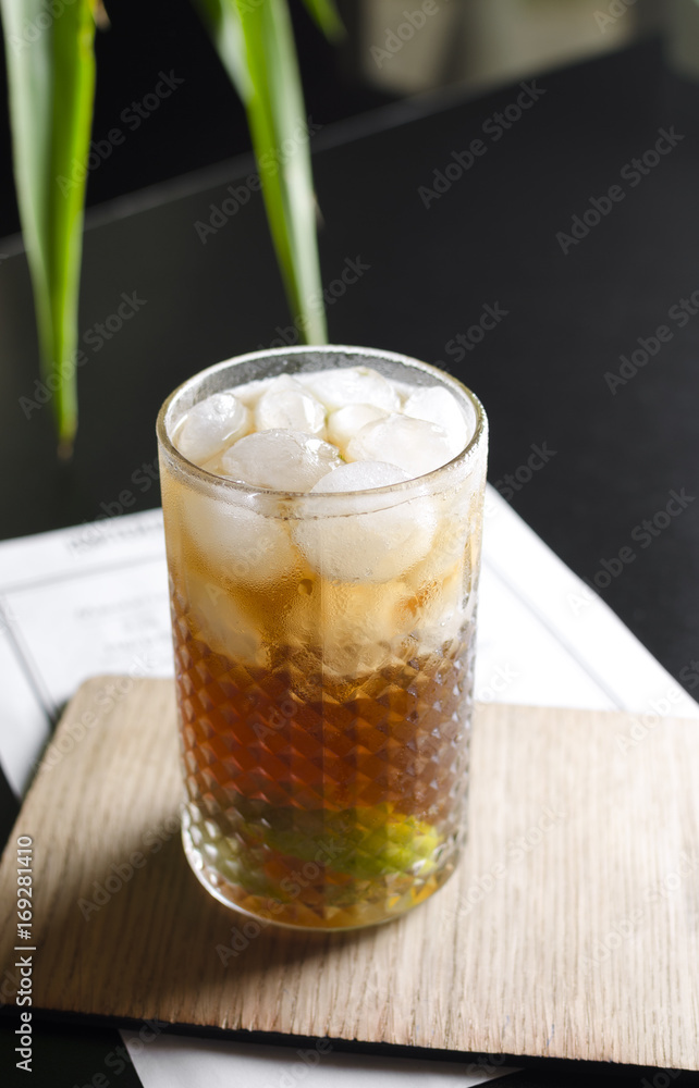 Cocktail cube libre on black table with palm tree on background Cocktail cube libre on black table with palm tree on background
