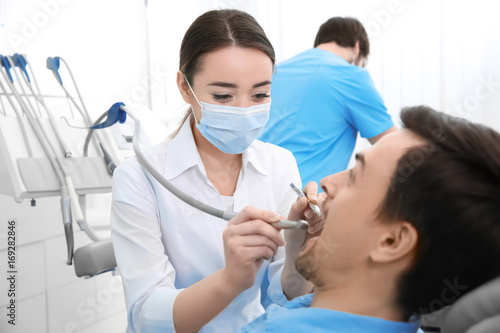 Dentist drilling patient's teeth in clinic