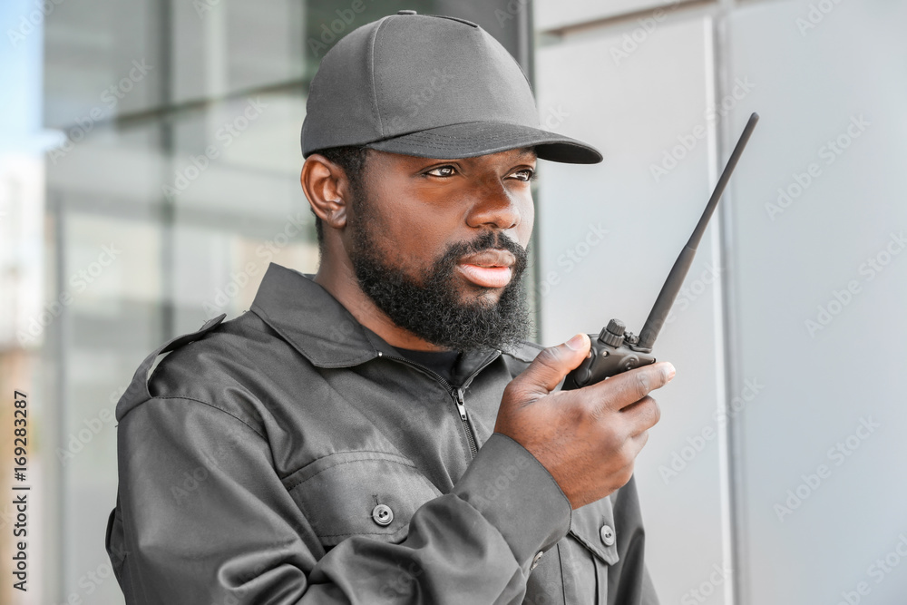 Male security guard using portable radio transmitter outdoors Male security guard using portable radio transmitter outdoors