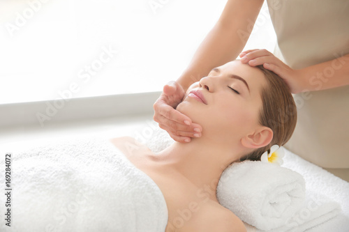 Young woman enjoying of facial massage in spa salon