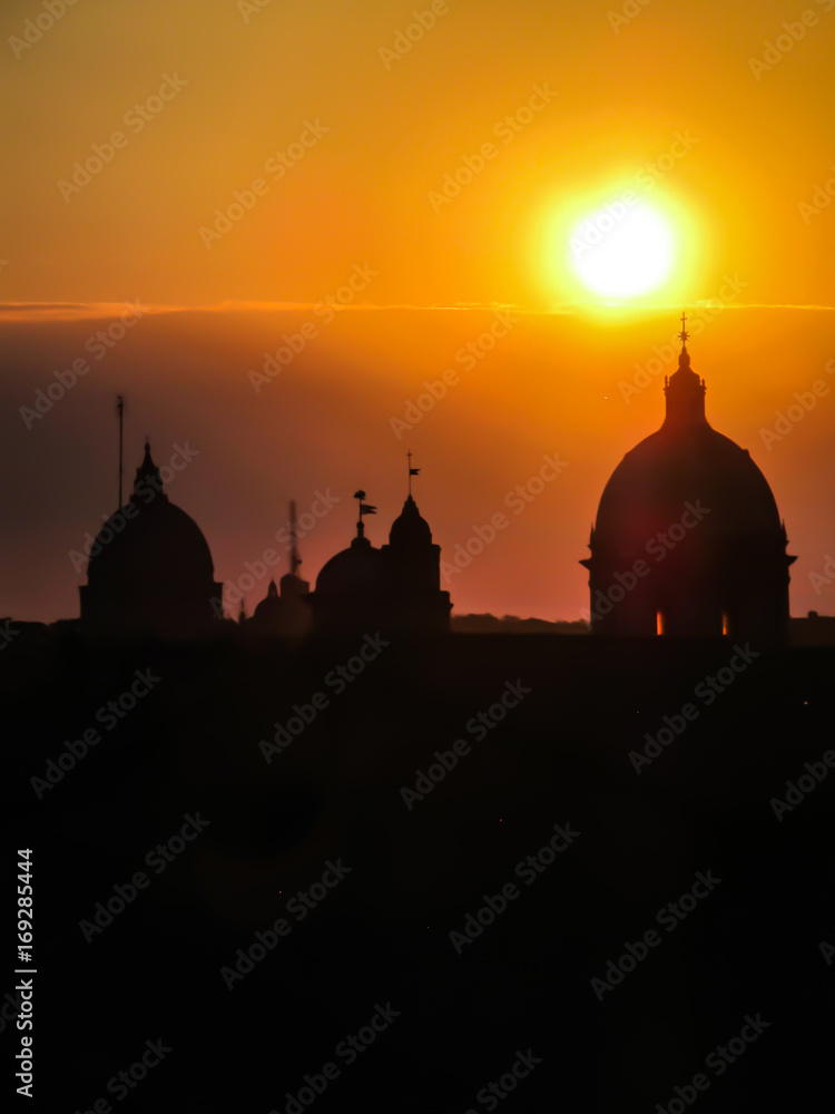 Sunset and Rome's cityscape with silhouette of church domes