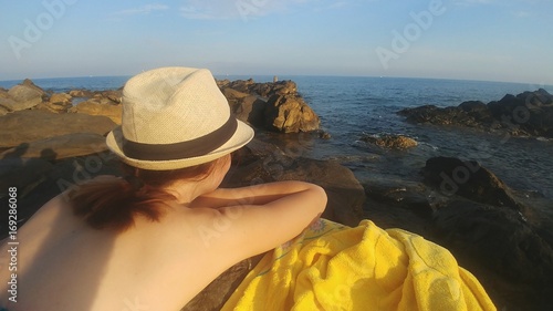 Ragazza con il cappello guarda il tramonto sul mare