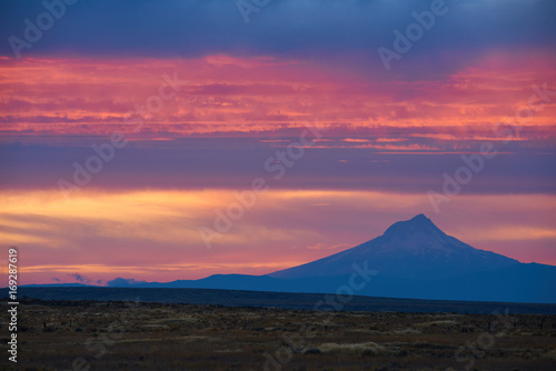 Colorful surrealistic Landscape with Mount Hood silhouette and dramatic clouds in the sky at sunset sunlight. View from viewpoint in Eastern Oregon USA Pacific Northwest. © thecolorpixels