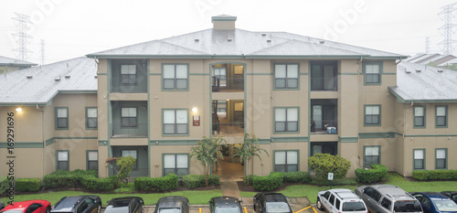 Harvey storm/hurricane heavy rain over a typical apartment complex building in suburban area at Humble, Texas, US. Parked cars on uncovered parking lot along apartment blocks. Severe weather. Panorama photo