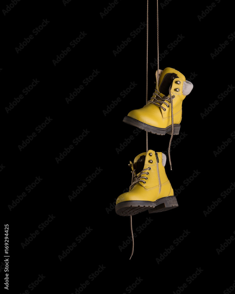 Timberland boots yellow on a black background. Boots hanging on laces.  Stock Photo | Adobe Stock
