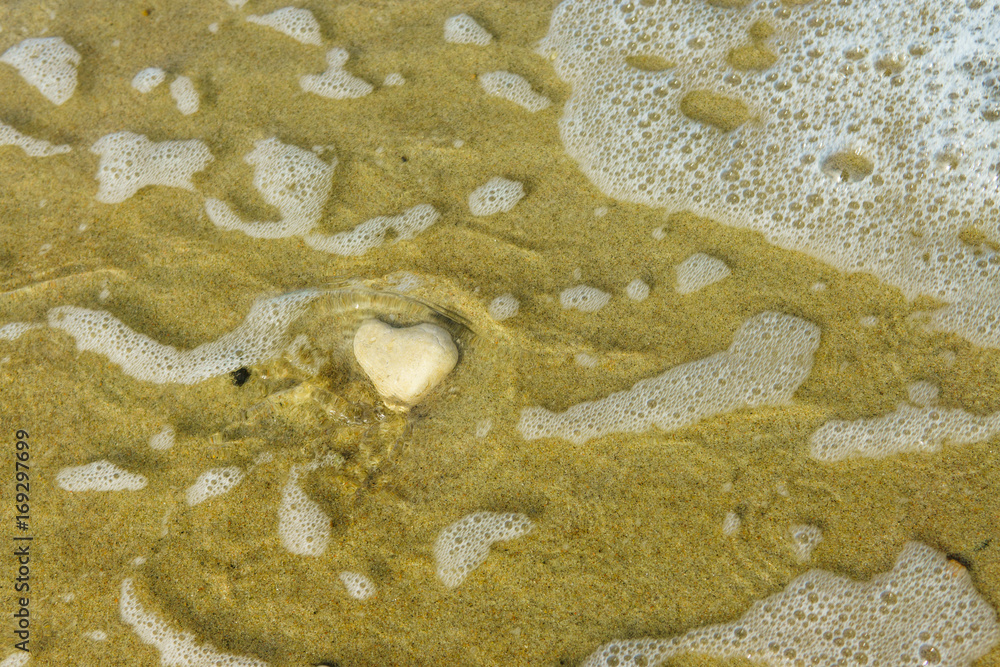 Obraz premium Stone in the form of a heart is washed by the sea