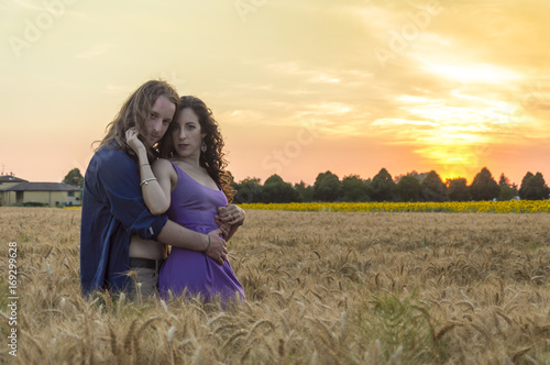 Young happy and romantic caucasian couple at grain field during sunset
