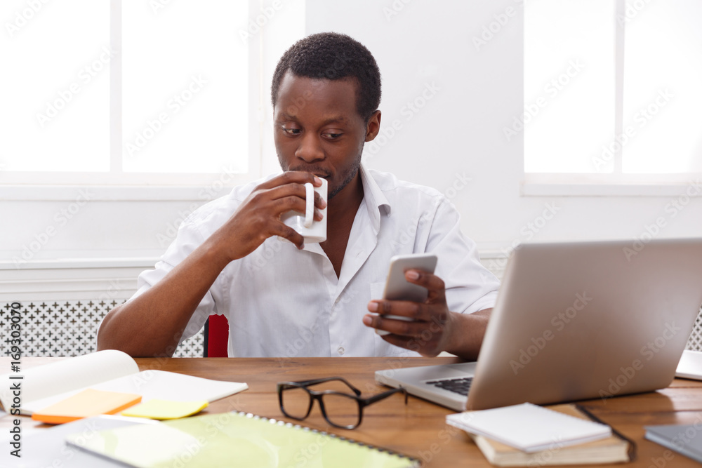 Young black businessman with mobile phone in modern white office Young black businessman with mobile phone in modern white office