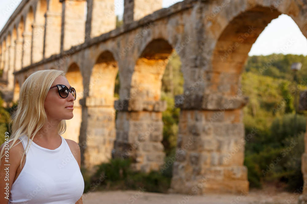 Woman posing near the  roman Aqueduct Pont del Diable in Tarragona at sunset