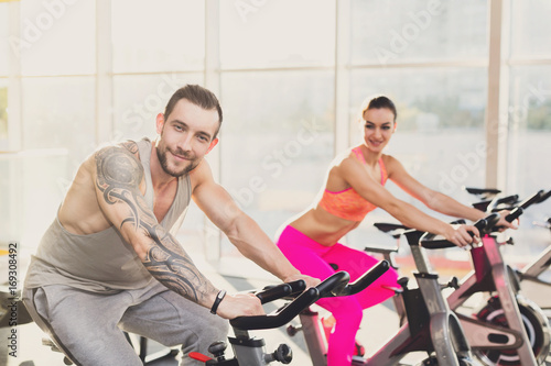 Fototapeta Naklejka Na Ścianę i Meble -  Man and woman, couple in gym on exercise bikes