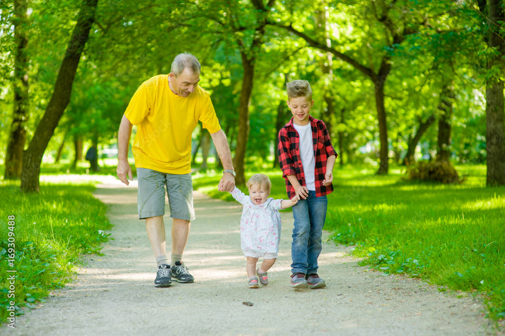 An elderly man walks with his grandchildren