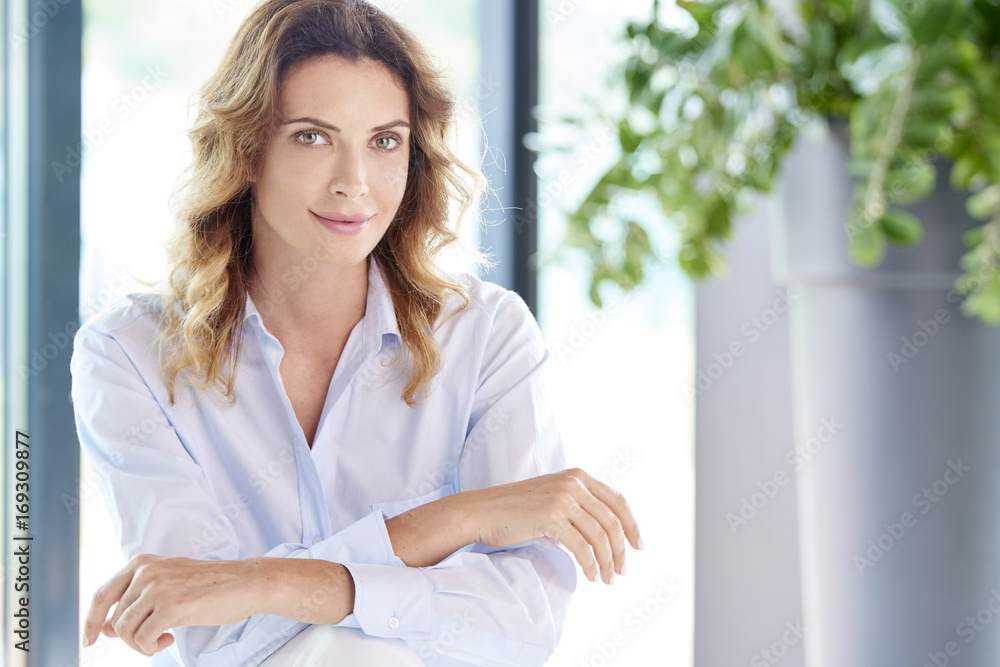 Smiling middle aged beauty. Portrait of a beautiful middle aged woman looking at camera and smiling while sitting at home. Smiling middle aged beauty. Portrait of a beautiful middle aged woman looking at camera and smiling while sitting at home.