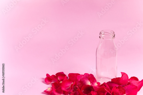 Empty bottle and rose petals On the pink background