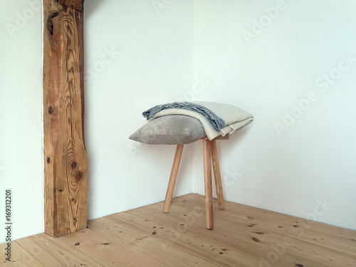 Kissen und Tagesdecke auf einem dreibeinigen Schemel aus Holz mit Holzbalken und Holzboden im alten Bauernhaus im Pfaffenwinkel in Rudersau bei Rottenbuch im Kreis Weilheim-Schongau in Oberbayern photo