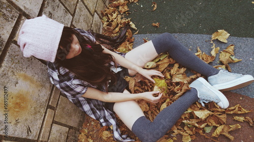 Chica adolescente jugando con hojas secas en un parque 