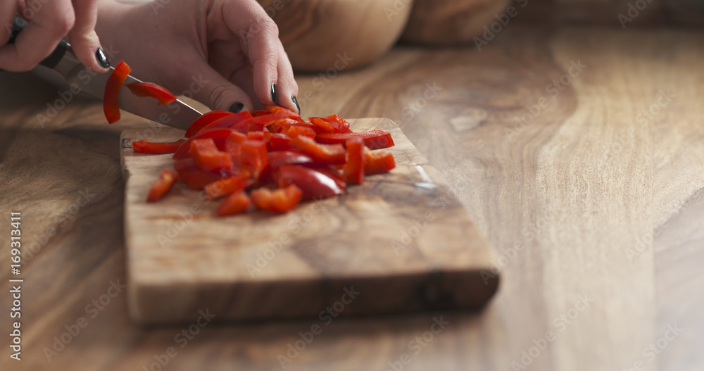 young female hand cutting bell pepper with knife
