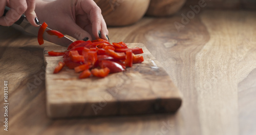 young female hand cutting bell pepper with knife