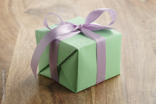 green paper gift box with purple ribbon bow on old wood table © GCapture