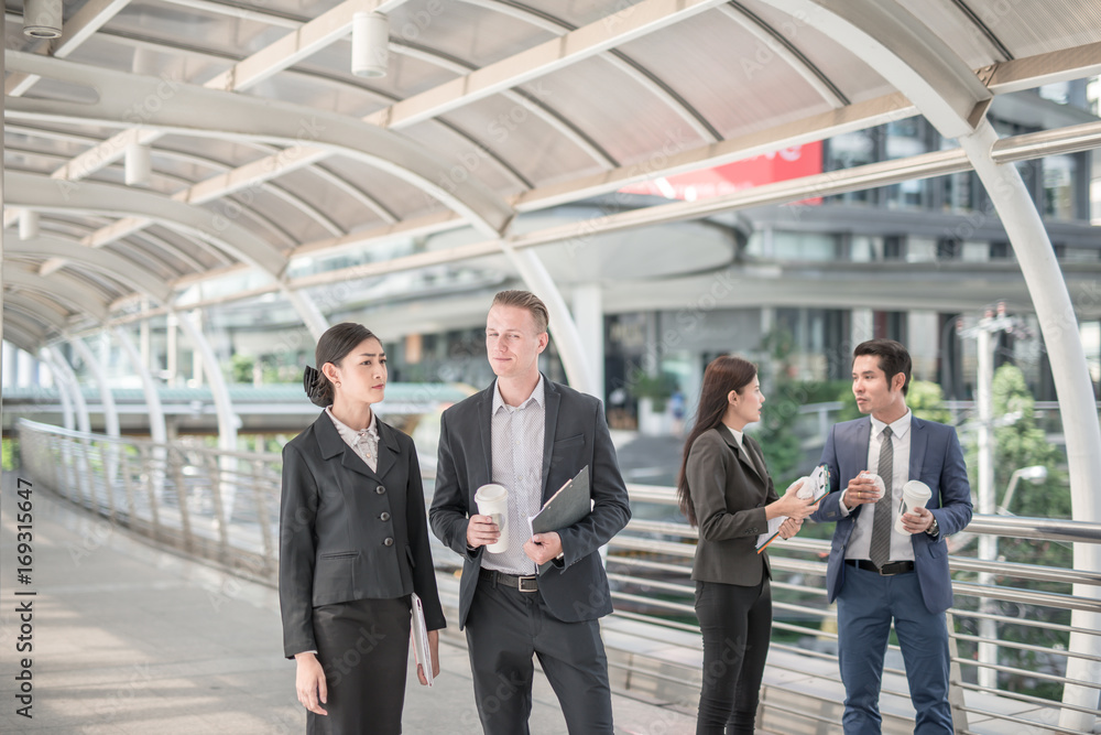 Happy Business colleagues walking outside office & talking to each other. Businessman talk and hold coffee cup Happy Business colleagues walking outside office & talking to each other. Businessman talk and hold coffee cup
