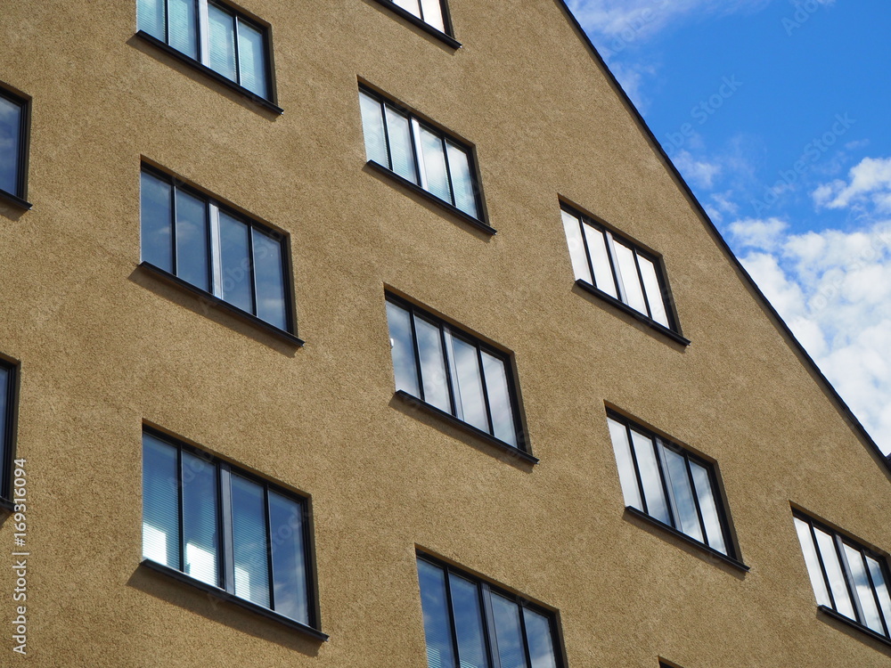 Obraz premium Hauswand beige mit Fenstern und spiegelnder Himmel