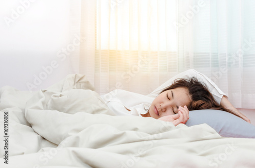 Young beautiful woman sleeping her bed and relaxing in the morning with sunray
