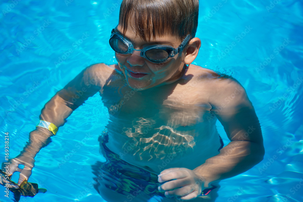 A boy, a child swims in the pool on a warm, summer day. Childhood, summer, swimming, swimming pool.
