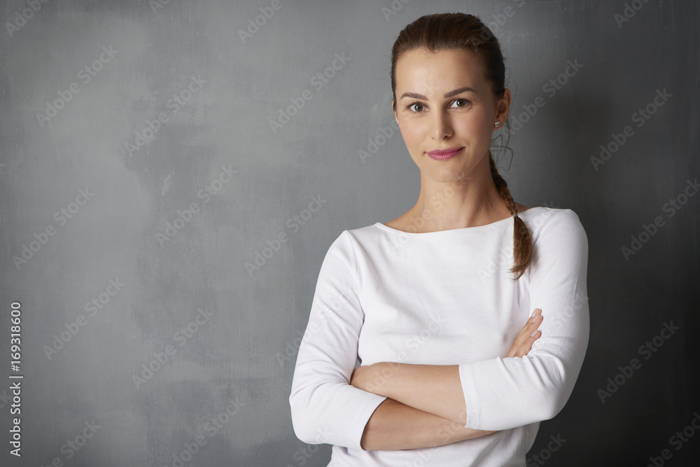 Happy young woman portrait. Studio shot of a beautiful young lady standing at grey wall. Happy young woman portrait. Studio shot of a beautiful young lady standing at grey wall.