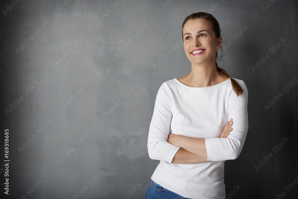 Happy young woman portrait. Studio shot of a beautiful young lady looking up while standing against grey wall. Happy young woman portrait. Studio shot of a beautiful young lady looking up while standing against grey wall.