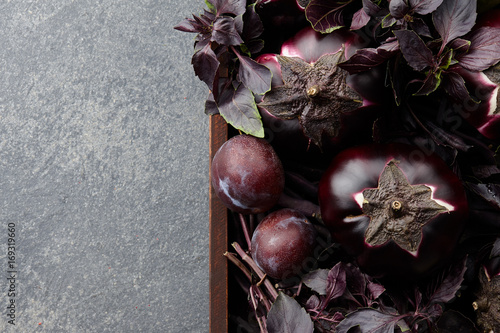 Obraz na plátně Wooden tray with purple vegetables and herbs on stone textured background