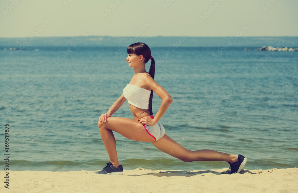 Young girl athlete, in shorts and top running on the beach in summer, morning exercise. Sports and healthy lifestyle.
