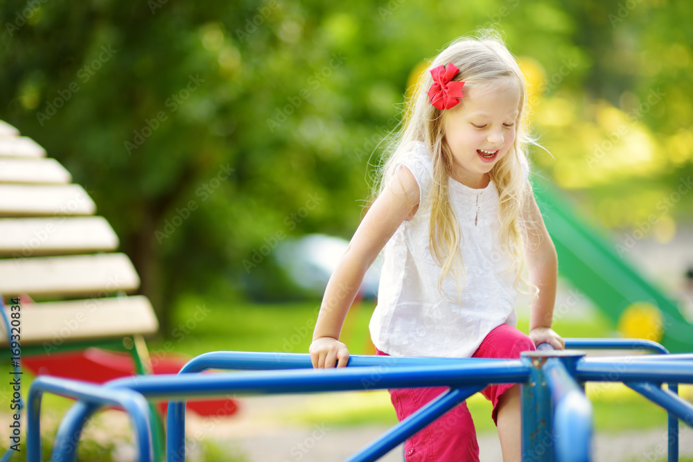 Cute little girl having fun on a playground outdoors in summer. Cute little girl having fun on a playground outdoors in summer.