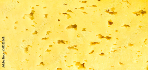 Cheese with small dirks, cut, background