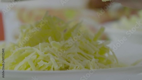 Woman is rubbing cheese on grater. Pieces of cheese hang down. Female hand rubs cheese on the grater photo