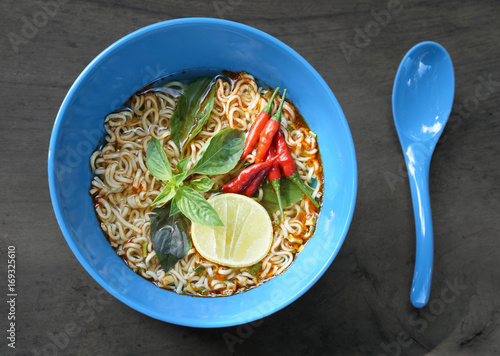 Wallpaper Mural Instant noodles in blue bowl put on dark wood background, Top view, red spicy chili, lime and green vegetables, junk food concept Torontodigital.ca