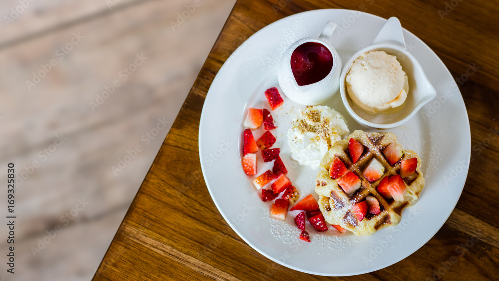Waffle strawberry with vanilla ice cream on the table with blurry background inside coffee shop Waffle strawberry with vanilla ice cream on the table with blurry background inside coffee shop