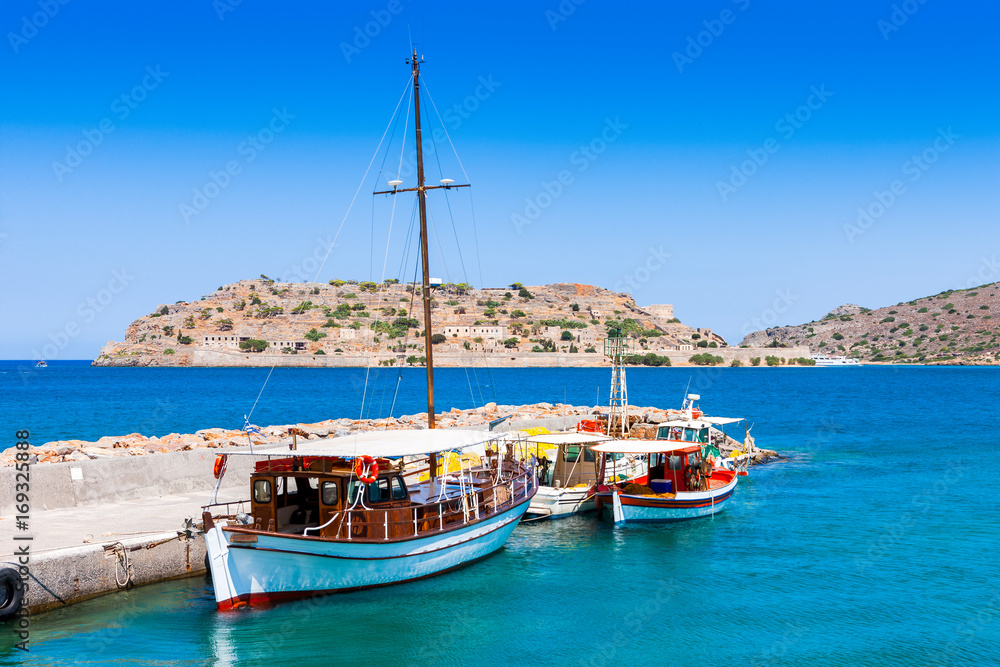 Tourist and fishing boats at the pier of the village of Plaka, near the island of Spinalonga. Crete