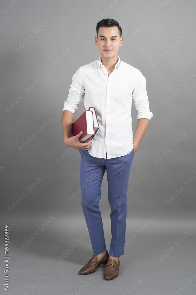 Portrait of man University student holding book in studio grey background Portrait of man University student holding book in studio grey background