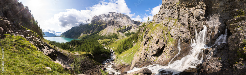 Panorama of torrent stream, lake, green valley in Alps mountains