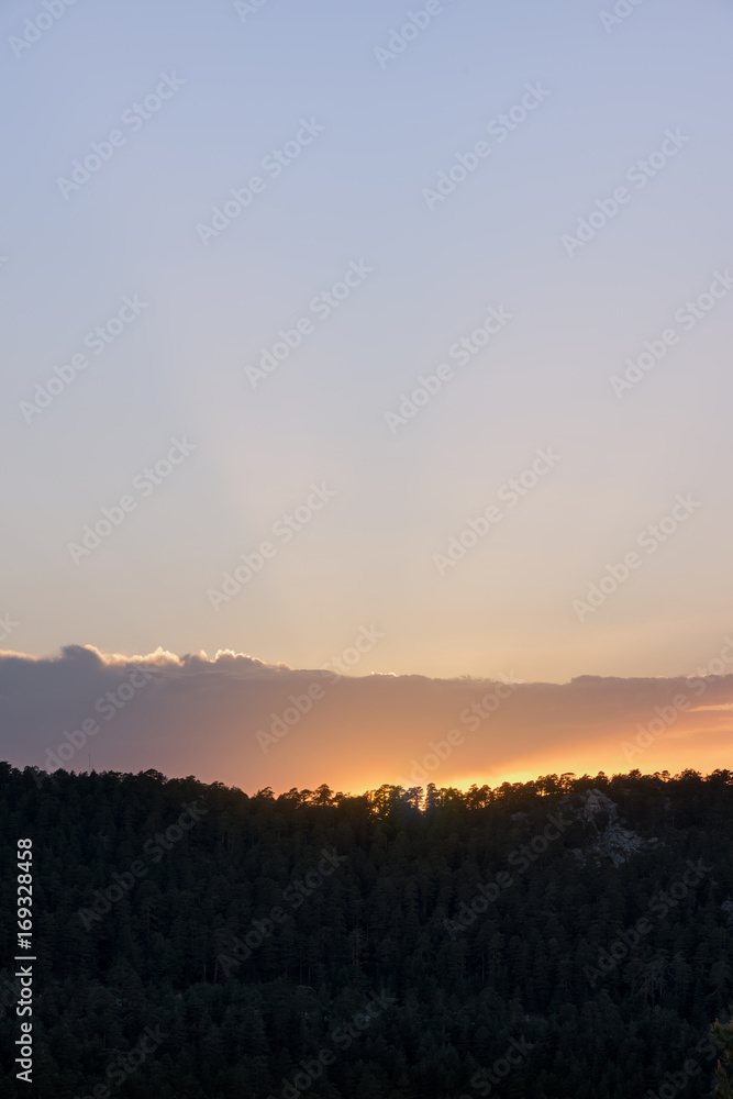 Beautiful sunrise in the morning clear sky with rays and mountain silhouette