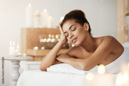 Beautiful african girl resting relaxing in spa salon with closed eyes.