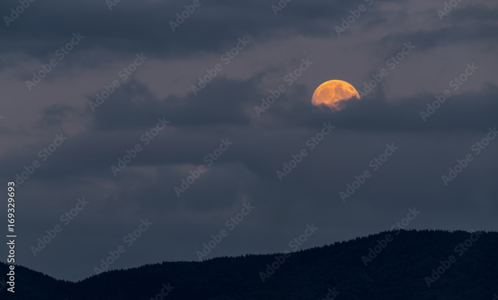 Full moon rising, half hidden behind clouds Full moon rising, half hidden behind clouds