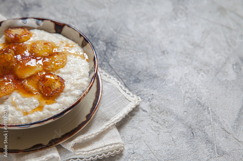 Bowl of oatmeal porridge with roasted banana and honey. healthy breakfast every day.
