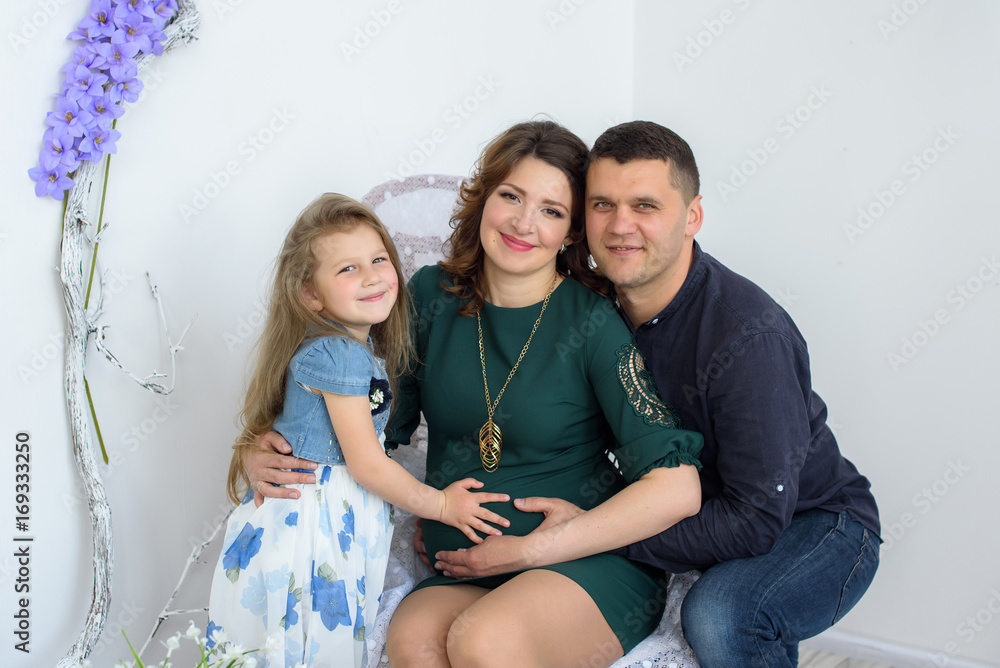 Happy pregnant family with little girl having fun at home