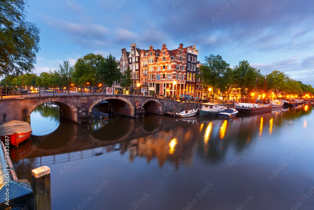 Fototapeta premium Kanał Amsterdamu, most i typowe domy, łodzie i rowery podczas niebieskiej godziny wieczornego zmierzchu, Holandia, Holandia. Używane tonowanie
