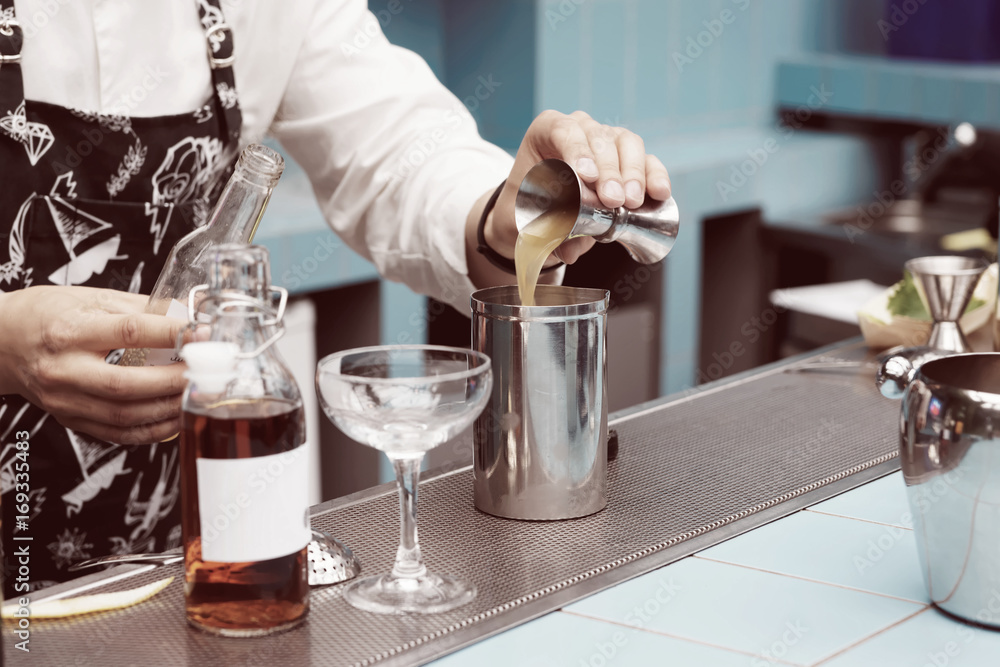 Bartender is pouring infusion into a mixing glass, toned Bartender is pouring infusion into a mixing glass, toned